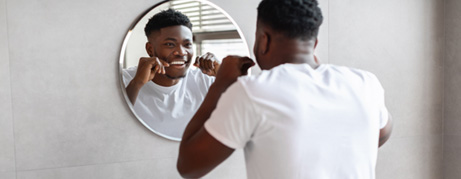 Man smiling while flossing his teeth