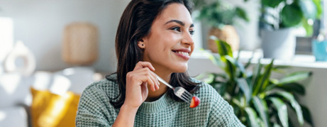 Woman smiling while eating healthy meal at home