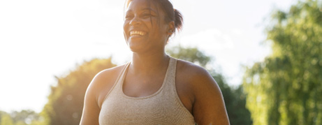 Smiling woman walking with yoga mat and water bottle