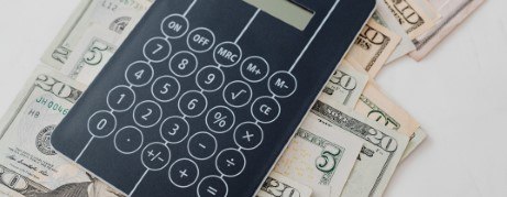 Calculator and cash on a white countertop