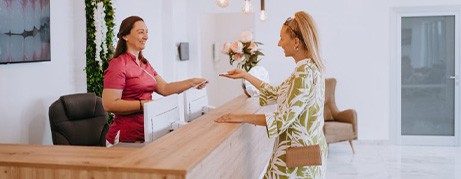 Dental receptionist assists patient at desk