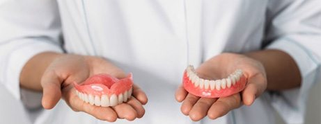 Dental team member holding upper and lower dentures