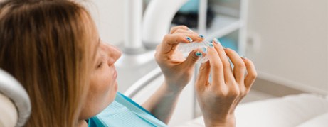 Smiling patient holding clear aligner